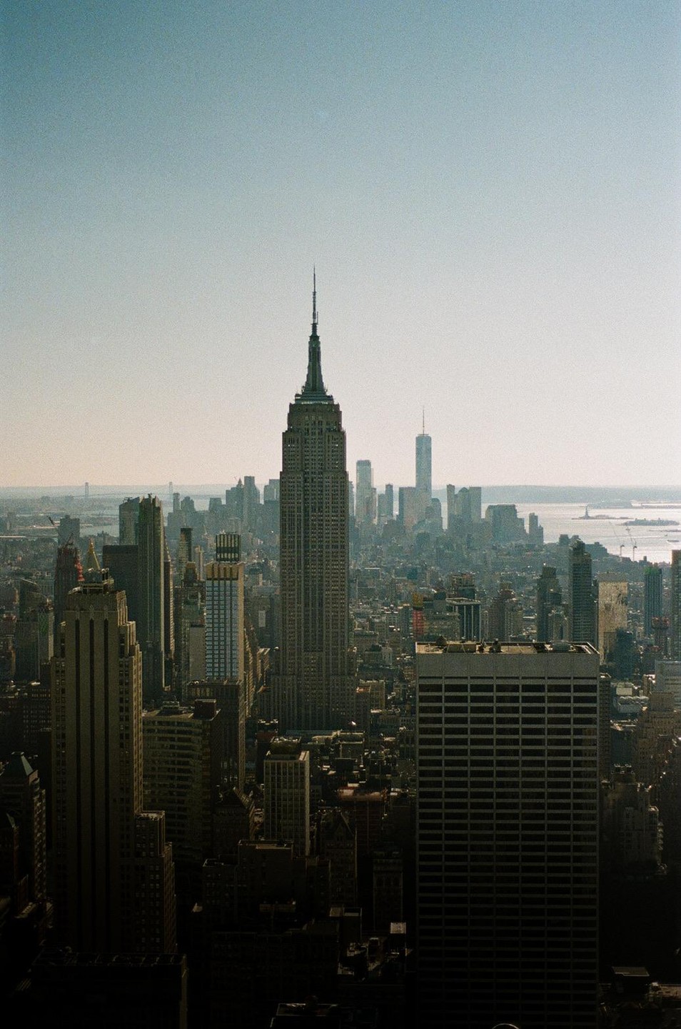 The Empire State Building stands tall among other skyscrapers in a hazy city.