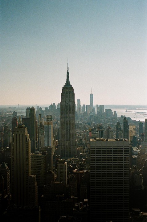 The Empire State Building stands tall among other skyscrapers in a hazy city.