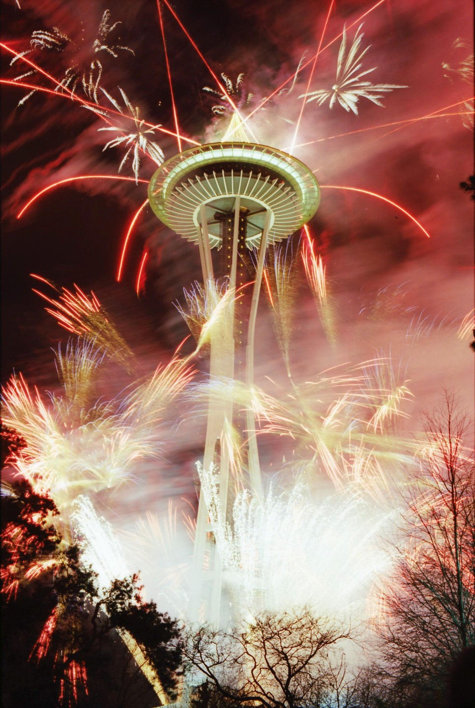 The Space Needle is surrounded by fireworks at night.