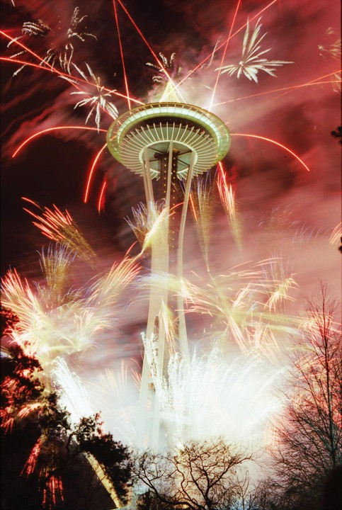 The Space Needle is surrounded by fireworks at night.