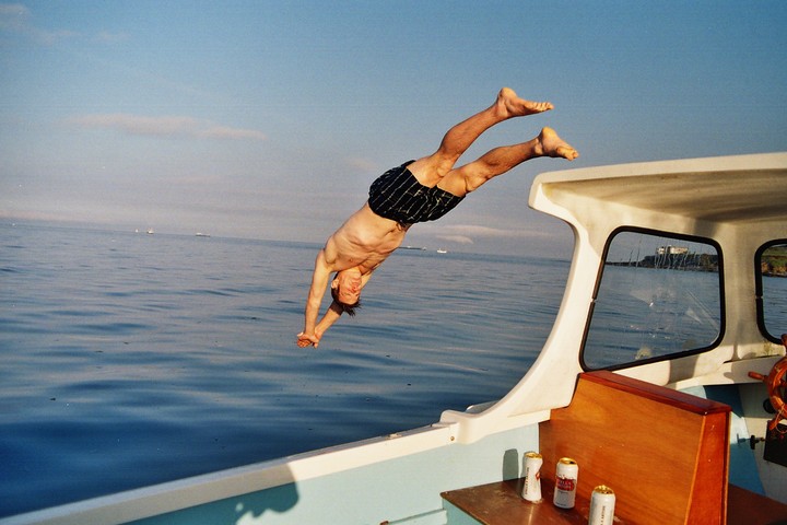 A man dives headfirst into the ocean from a boat.