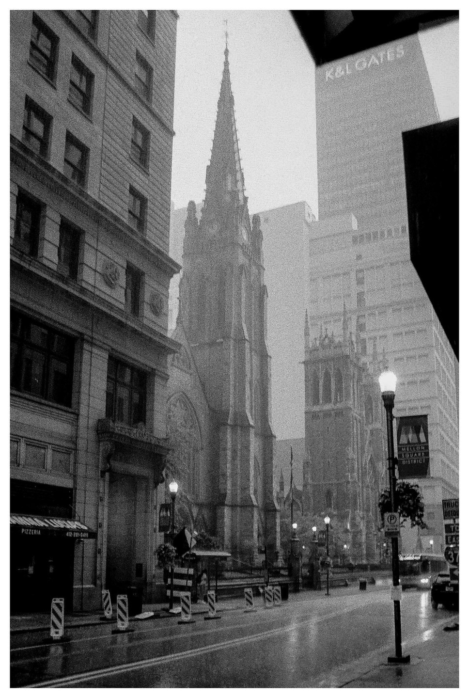 A street with a church and other buildings is wet from rain.