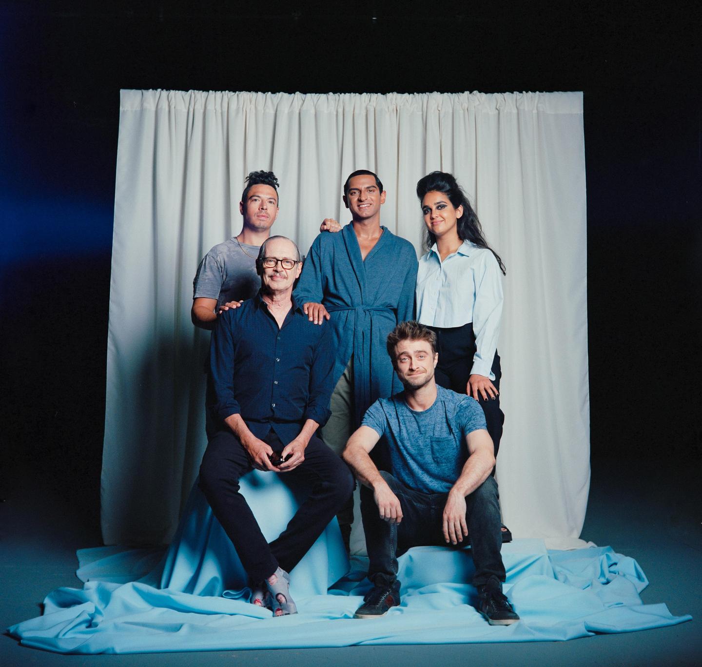 Five people pose for a group portrait in front of a white curtain and blue fabric.