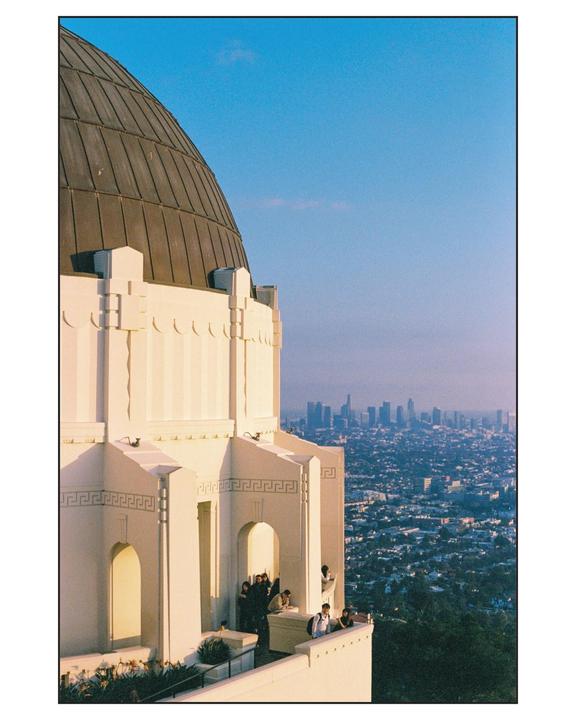 A large white building with a domed roof overlooks a city skyline in the distance.