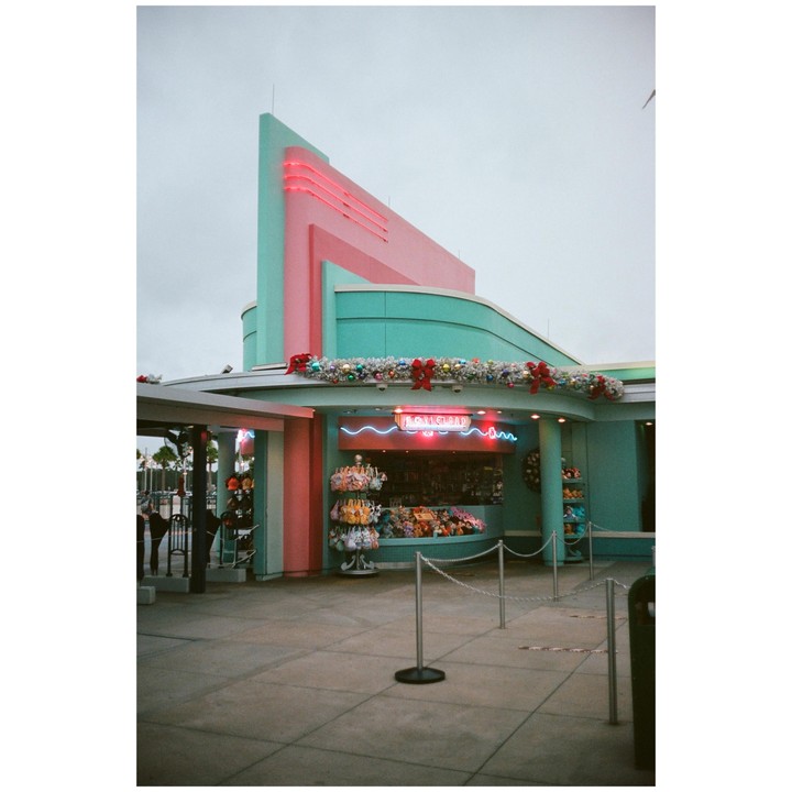 A building with pink and teal walls and neon lights is decorated with garlands and bows.