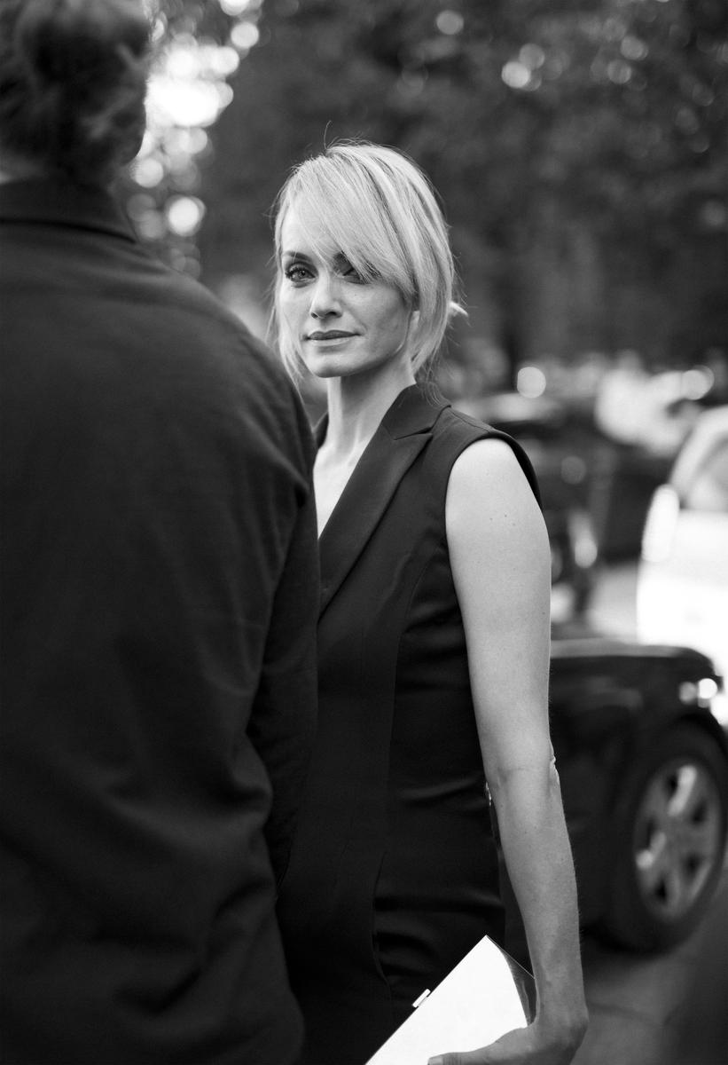 A woman with blonde hair looks over her shoulder at the viewer while standing next to a man.