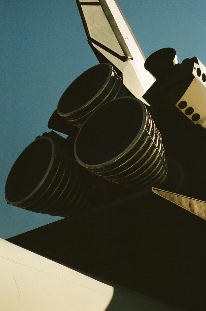 The engines of a space shuttle are visible against a clear sky.