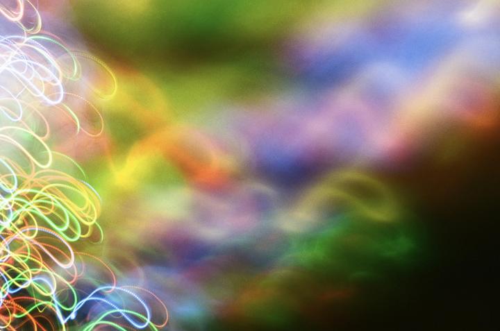 A colorful abstract image features swirling light trails on the left against a blurred background of various hues.