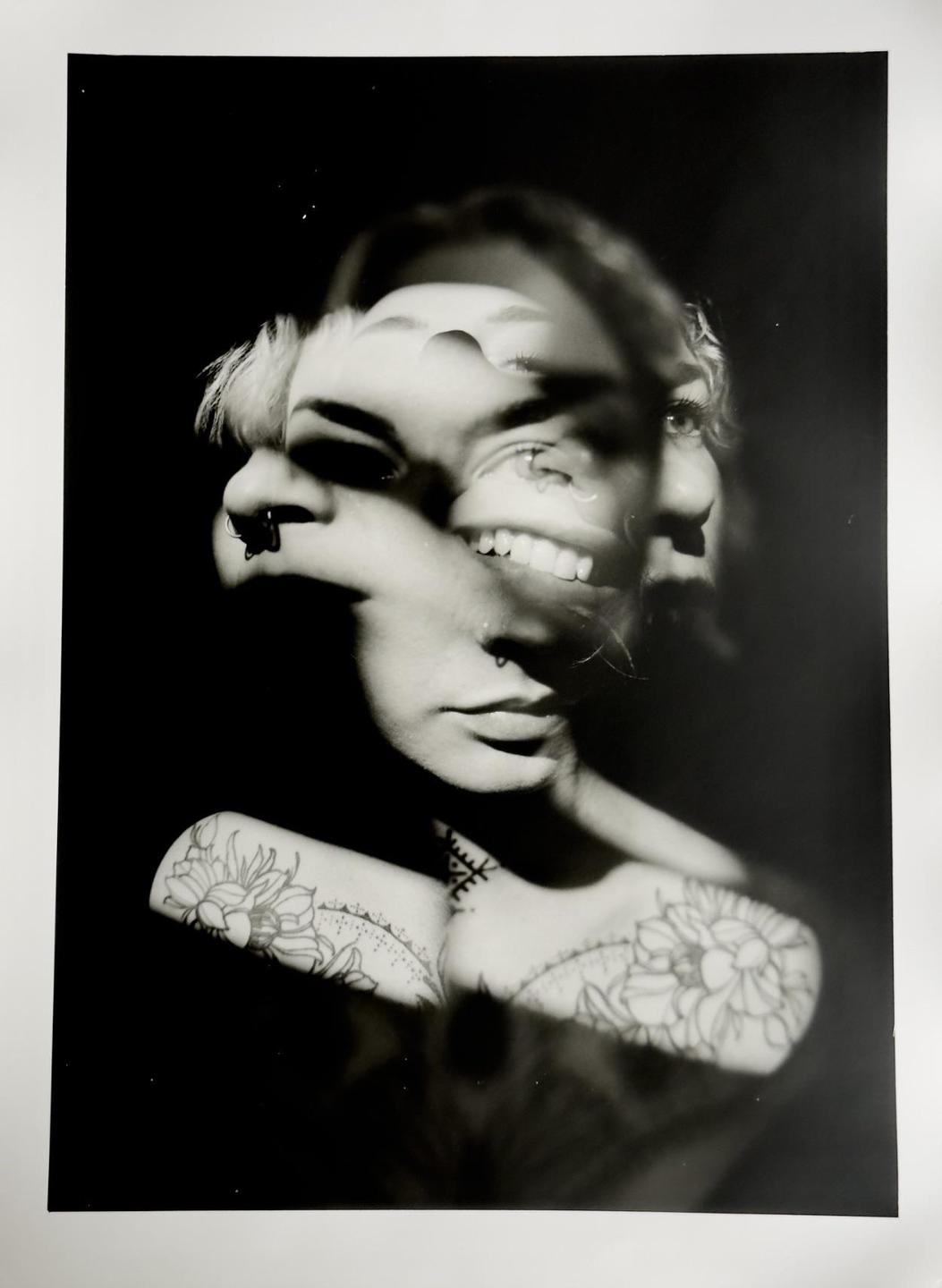A woman's face is shown in multiple exposures with tattoos visible on her shoulders.