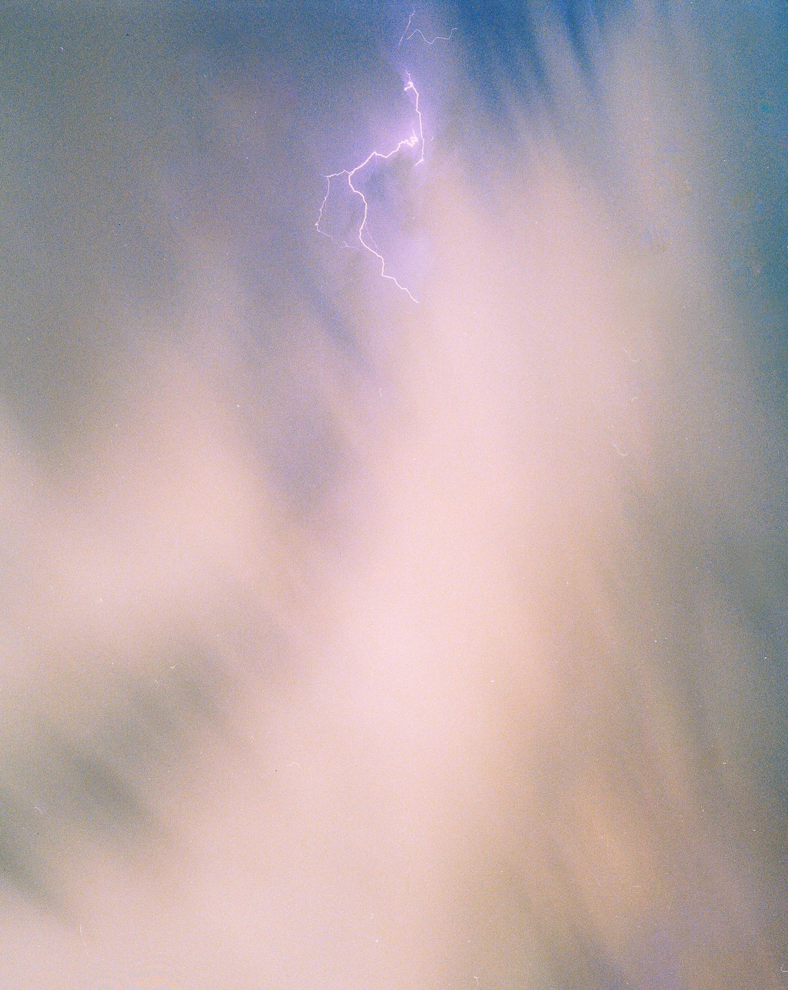A bright lightning bolt illuminates a cloudy sky.