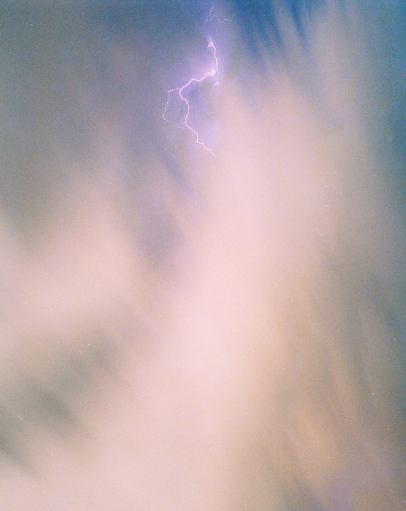 A bright lightning bolt illuminates a cloudy sky.