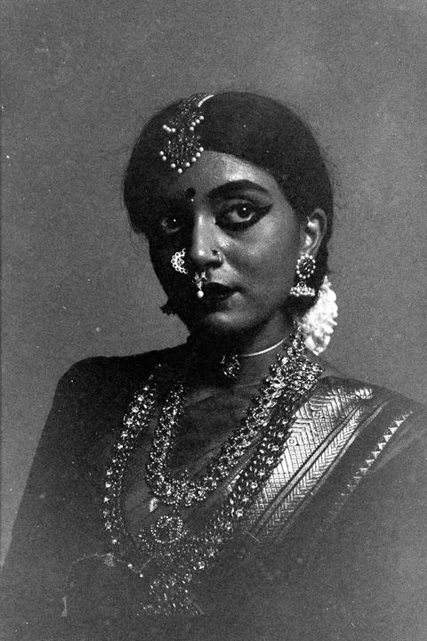 A woman in traditional Indian attire and jewelry looks directly at the viewer.