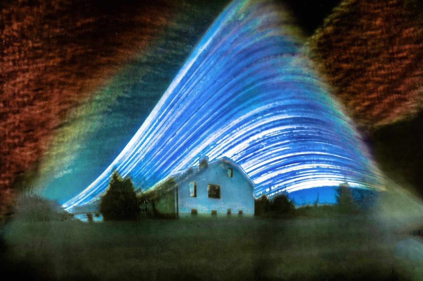 A house sits under a sky filled with blue and white light trails.