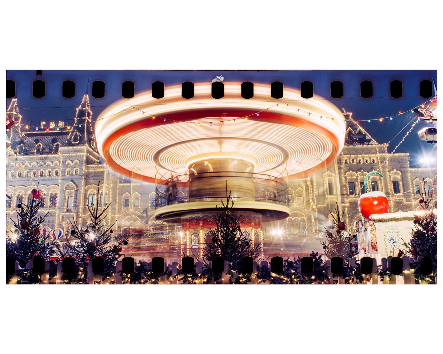A carousel spins in front of an illuminated building at night.