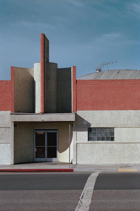 A building with red and beige walls features an art deco facade and a glass block window.