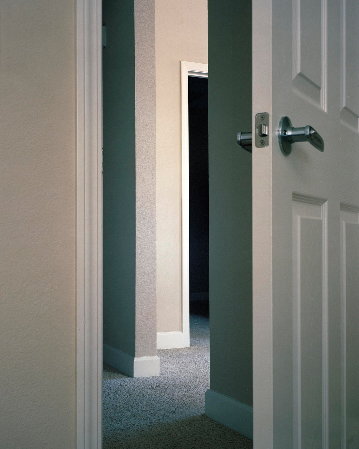 A series of open doors and walls create a layered perspective of a hallway with carpet.