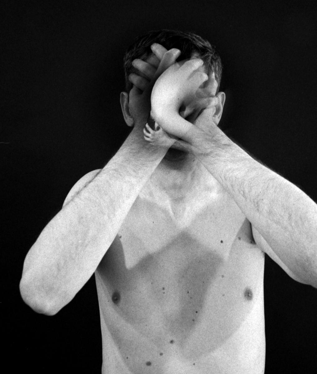 A man covers his face with his hands, which are also covered by a child's hands in a double exposure.