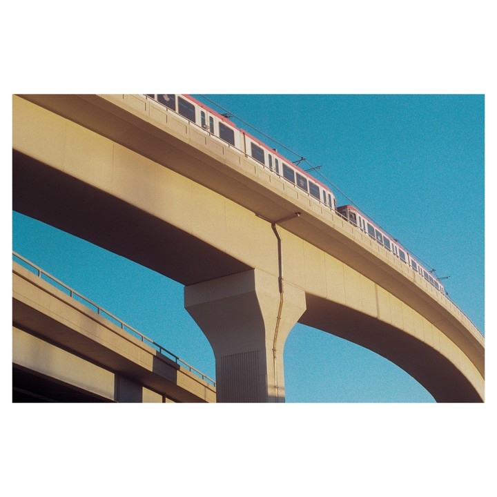 A train travels on an elevated track with a clear blue sky in the background.