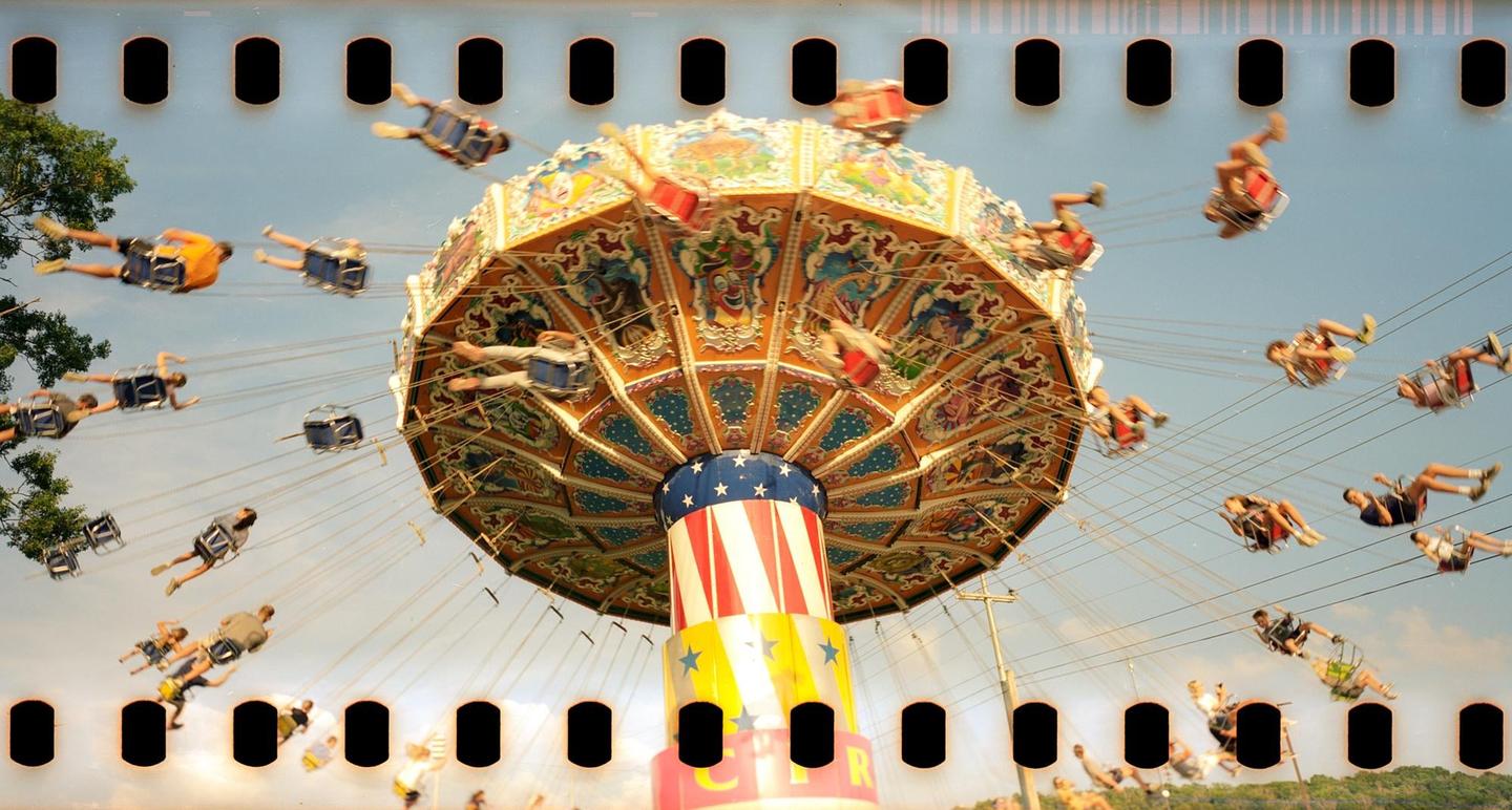 People are riding a swing ride at a summer fair.