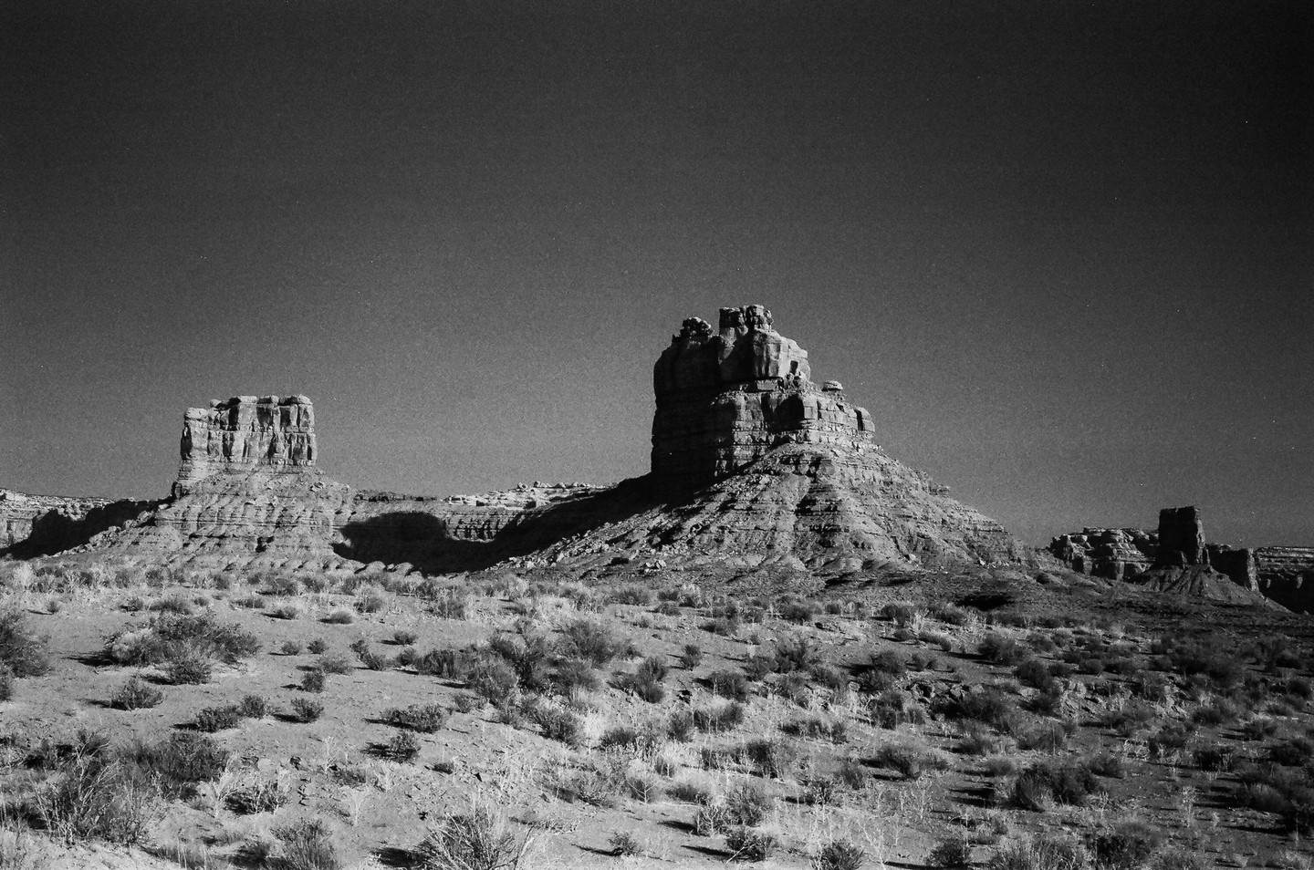 Two large rock formations stand in a desert landscape under a clear sky.