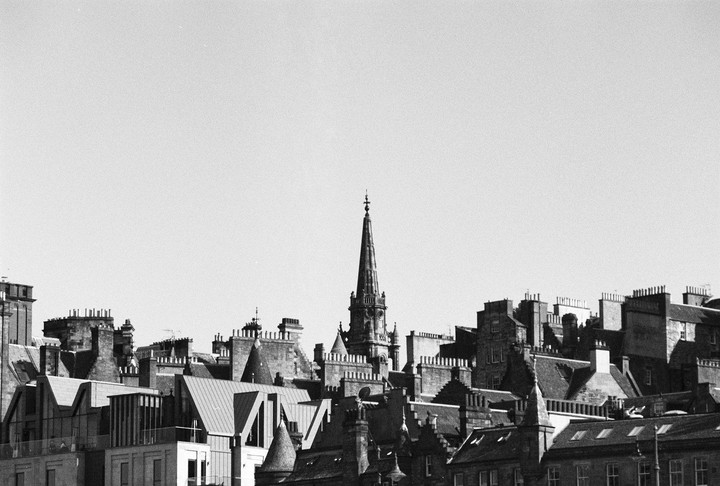 A tall, ornate spire rises above a dense collection of rooftops and chimneys.
