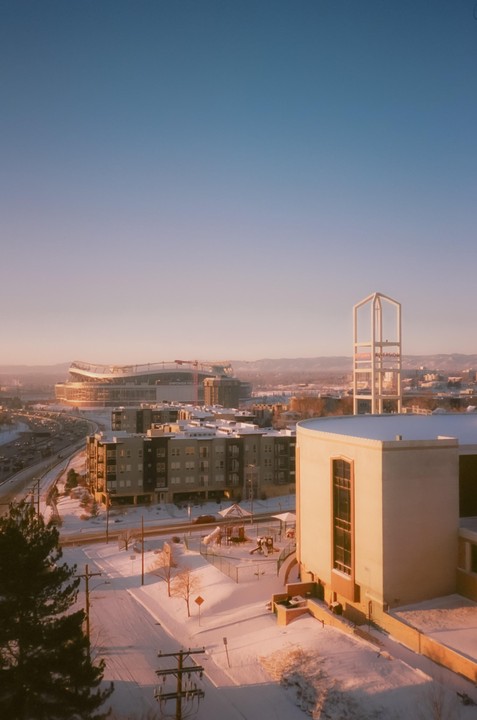 A snowy city with a stadium and buildings is visible under a clear sky.