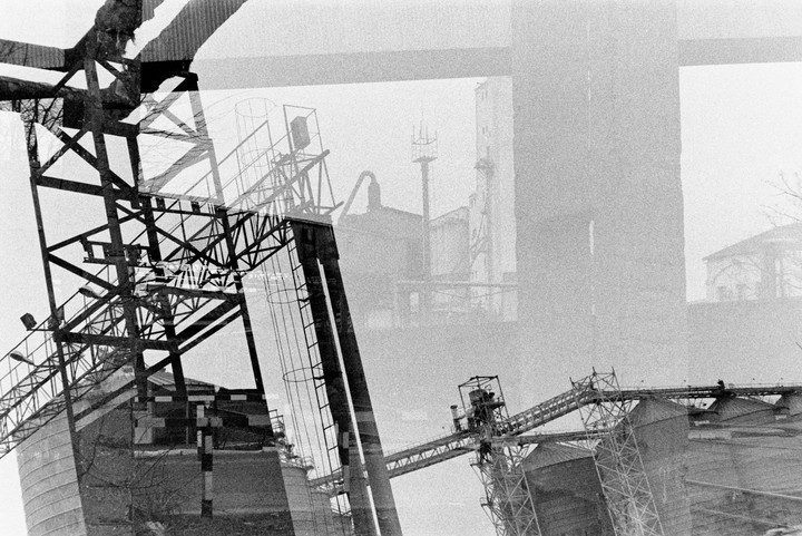 A double exposure shows industrial structures and buildings in a hazy environment.