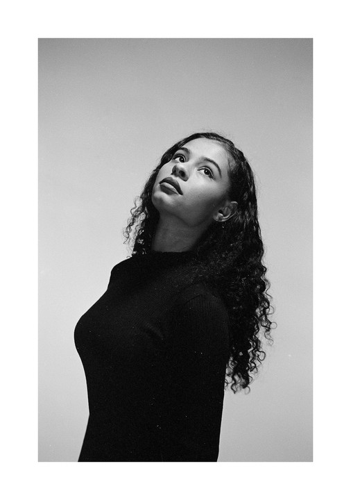 A woman with curly hair looks up and to the right.