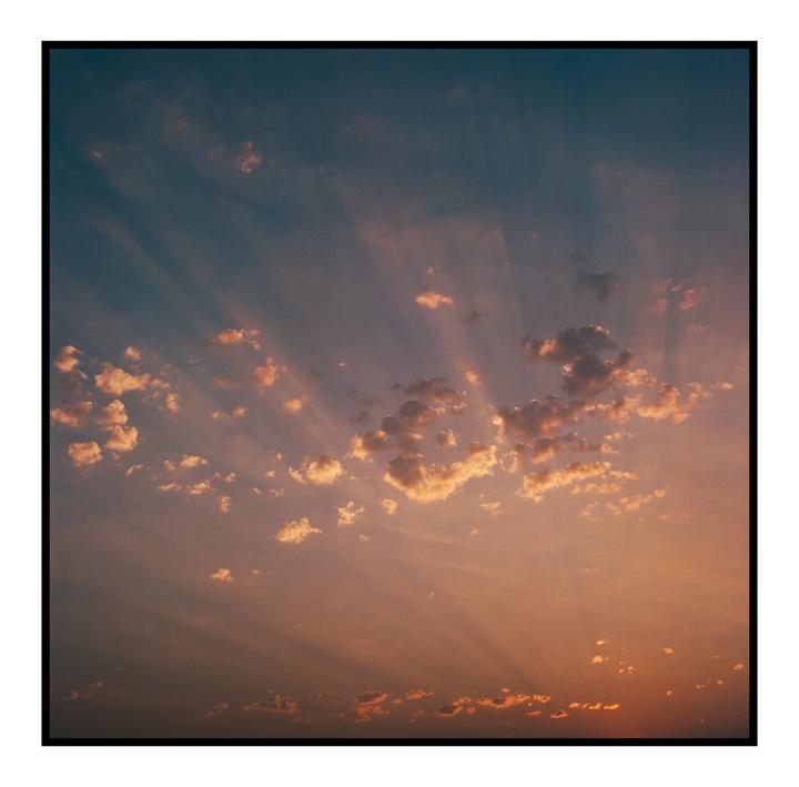 Sun rays stream through clouds in a colorful sky.