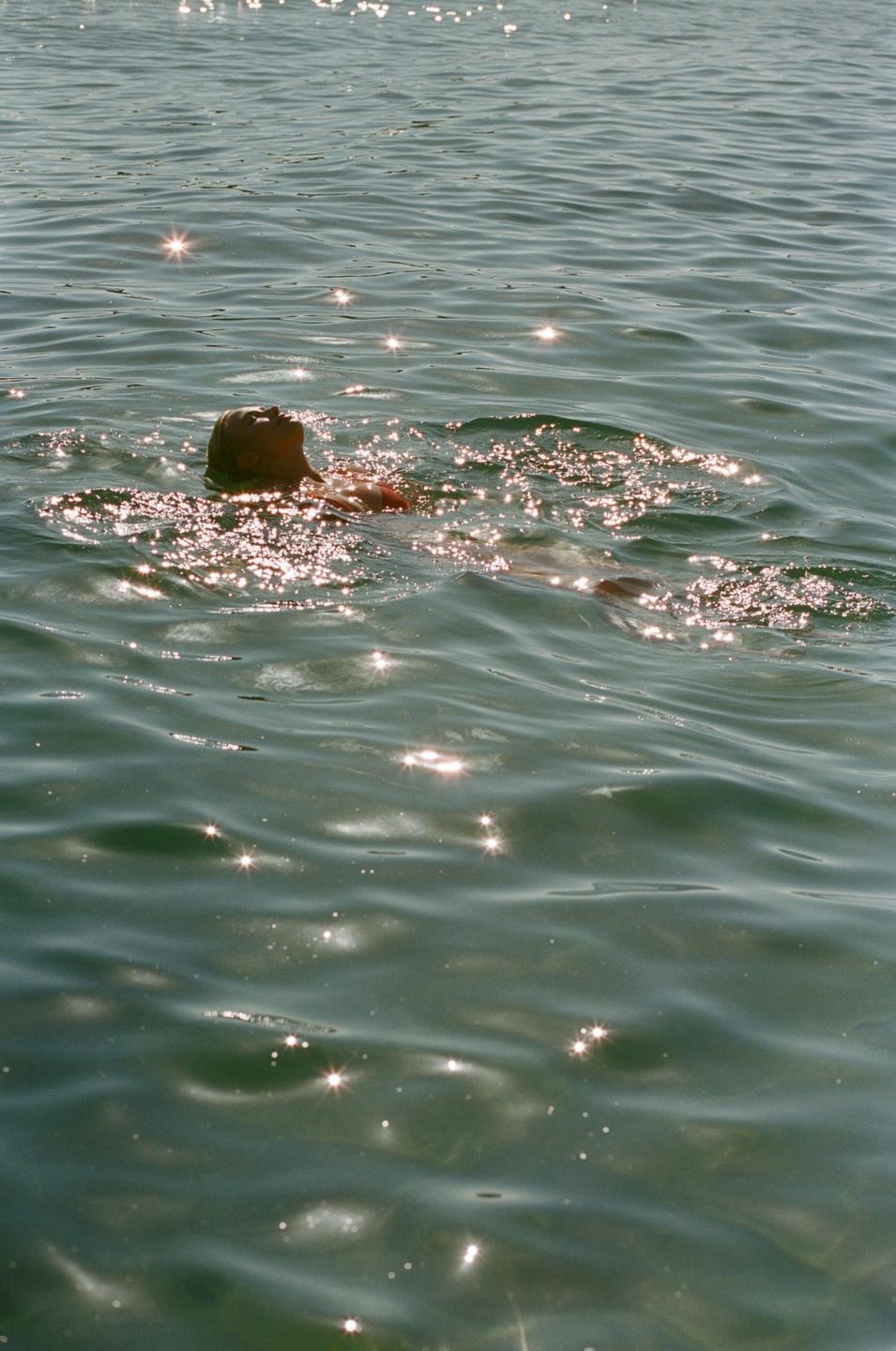 A woman floats on her back in sparkling water.