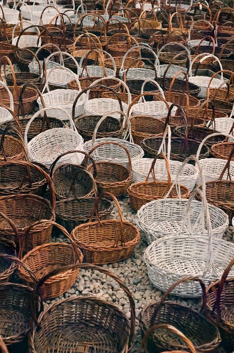 Hundreds of woven baskets are arranged on a gravel surface.