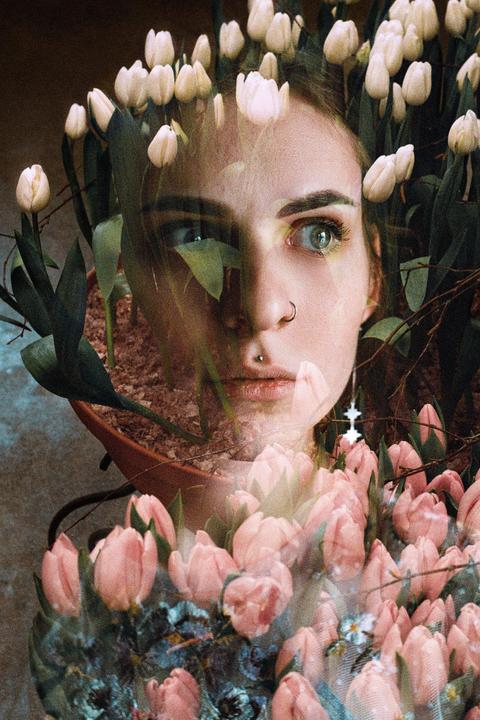 A woman's face is double exposed with white and pink tulips and a potted plant.
