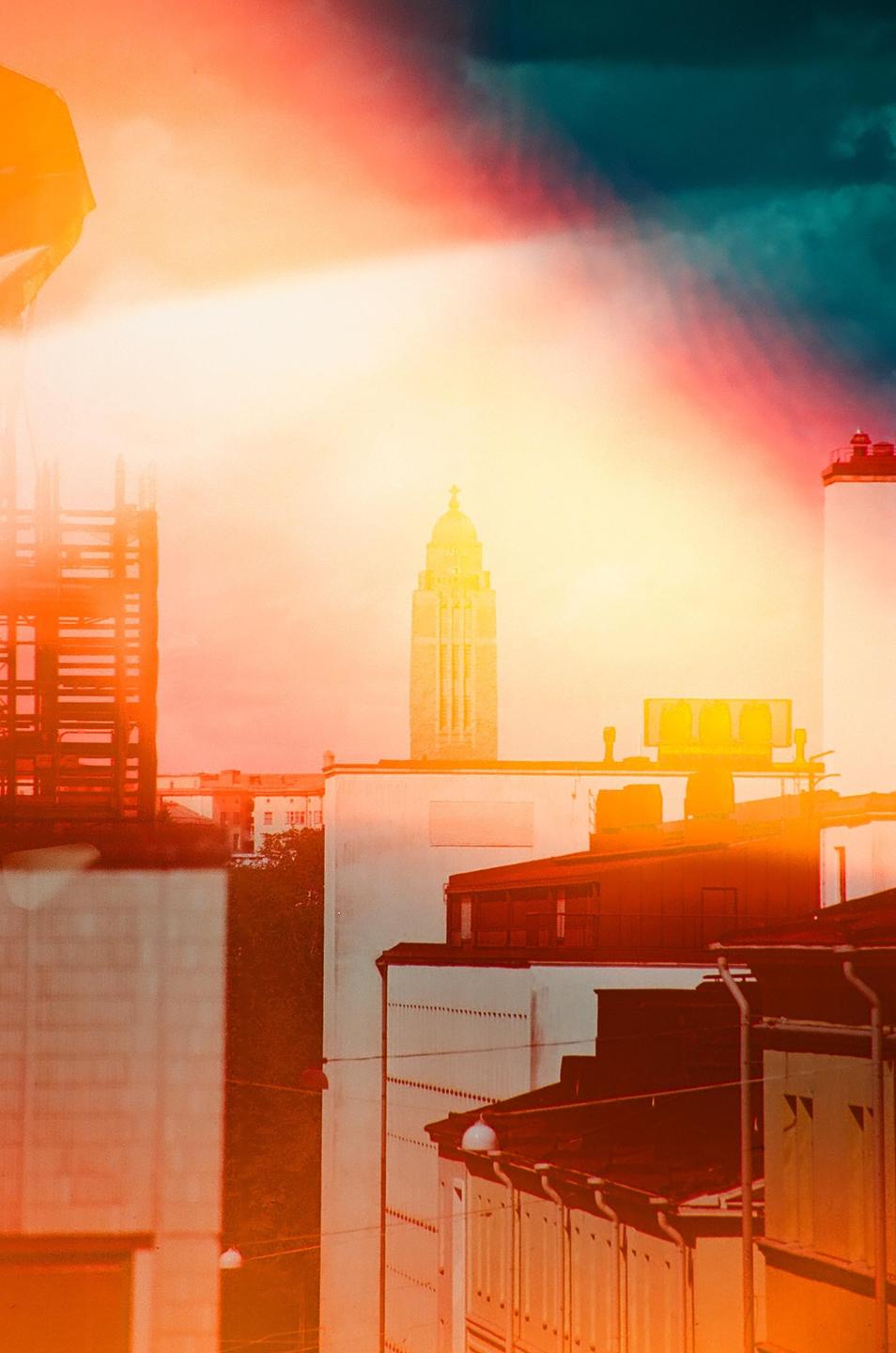 A tall, ornate tower rises above a city skyline, with a bright, colorful sky overhead.