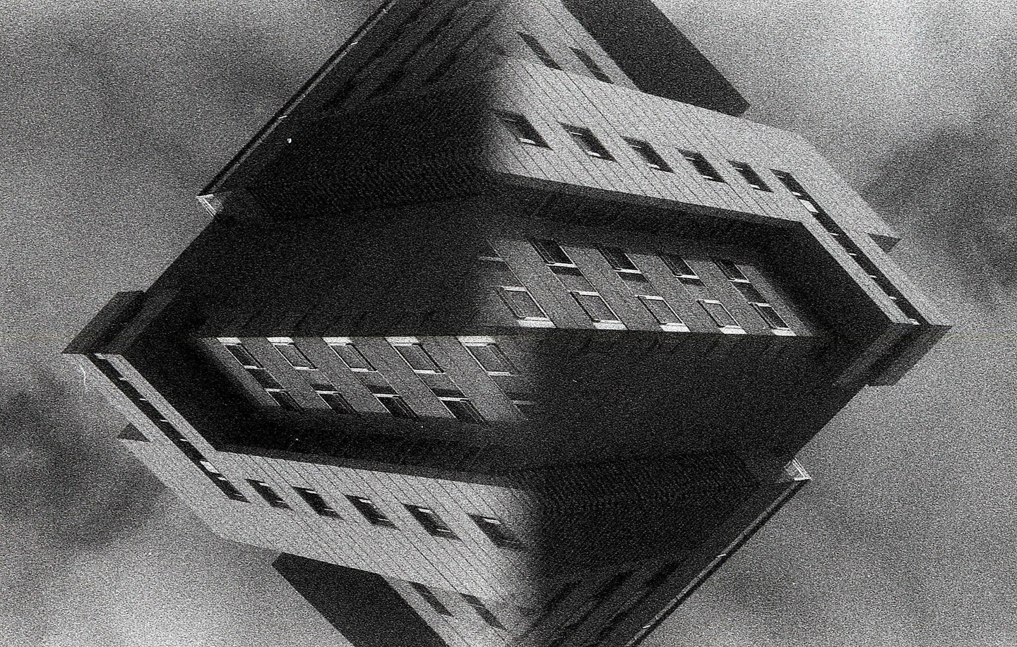 A black and white abstract image shows a building reflected to create a diamond shape.