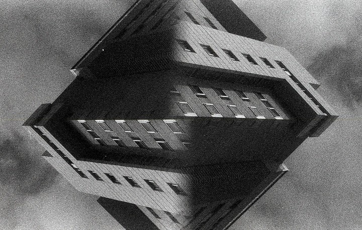 A black and white abstract image shows a building reflected to create a diamond shape.