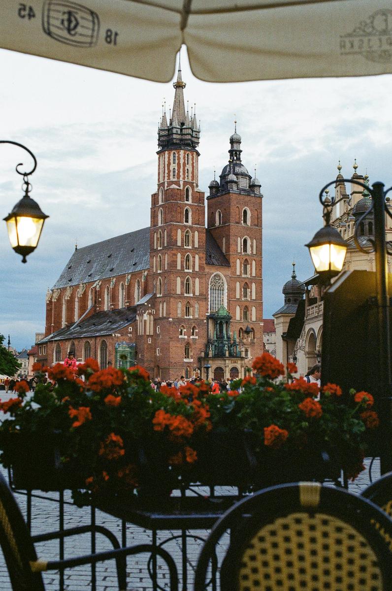 A large brick church with two towers stands behind flower boxes and cafe seating.
