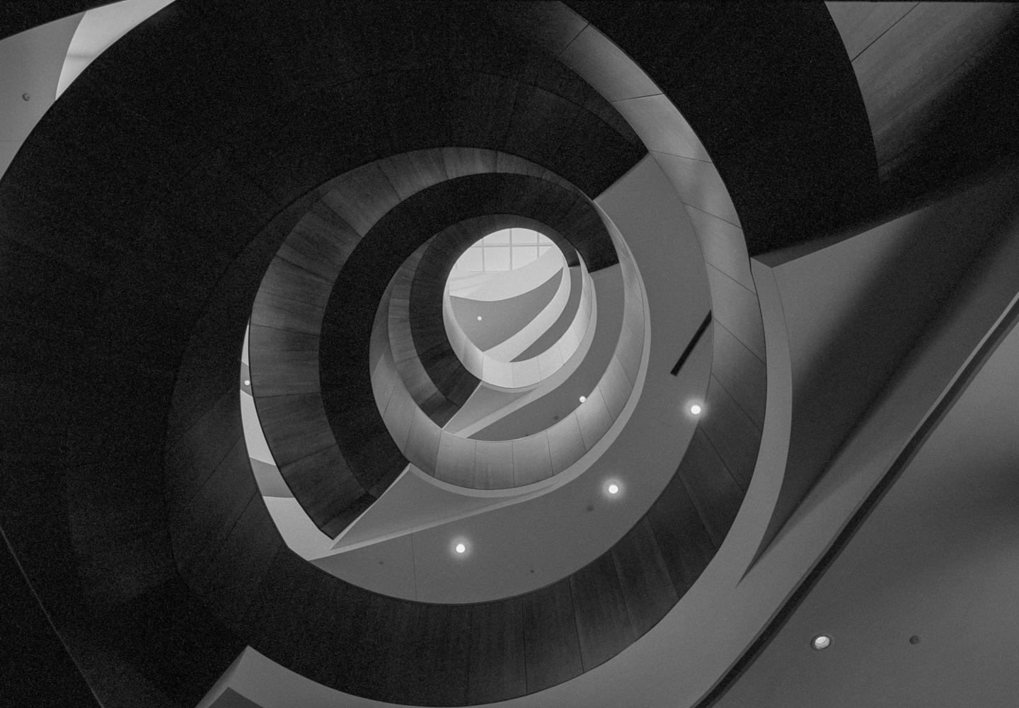 A low-angle view shows a spiral staircase with a skylight at the top.