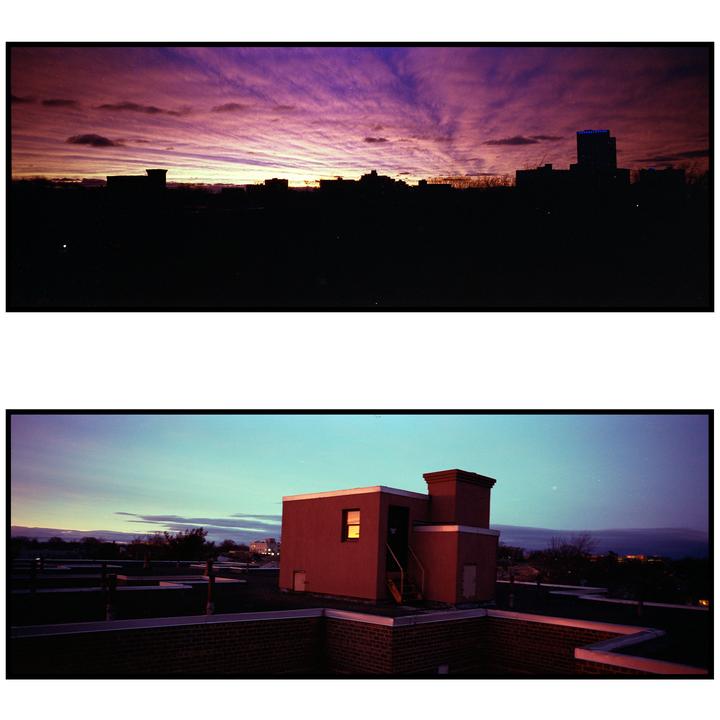 A panoramic view shows a sunset over a city skyline and a building on a rooftop.
