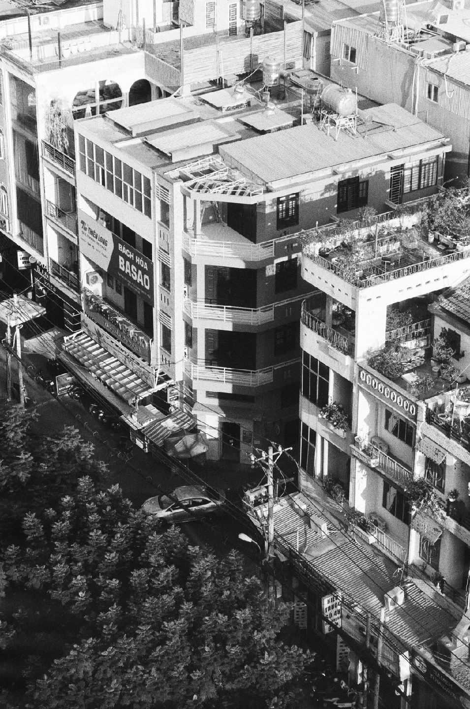 An aerial view shows a street with buildings, trees, and a car.