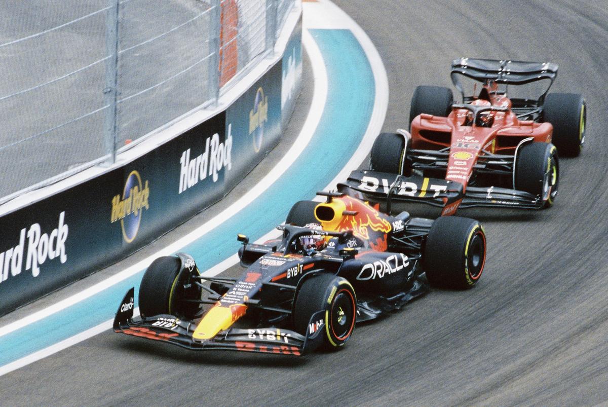 Two race cars are speeding around a track with a Hard Rock barrier visible on the left.