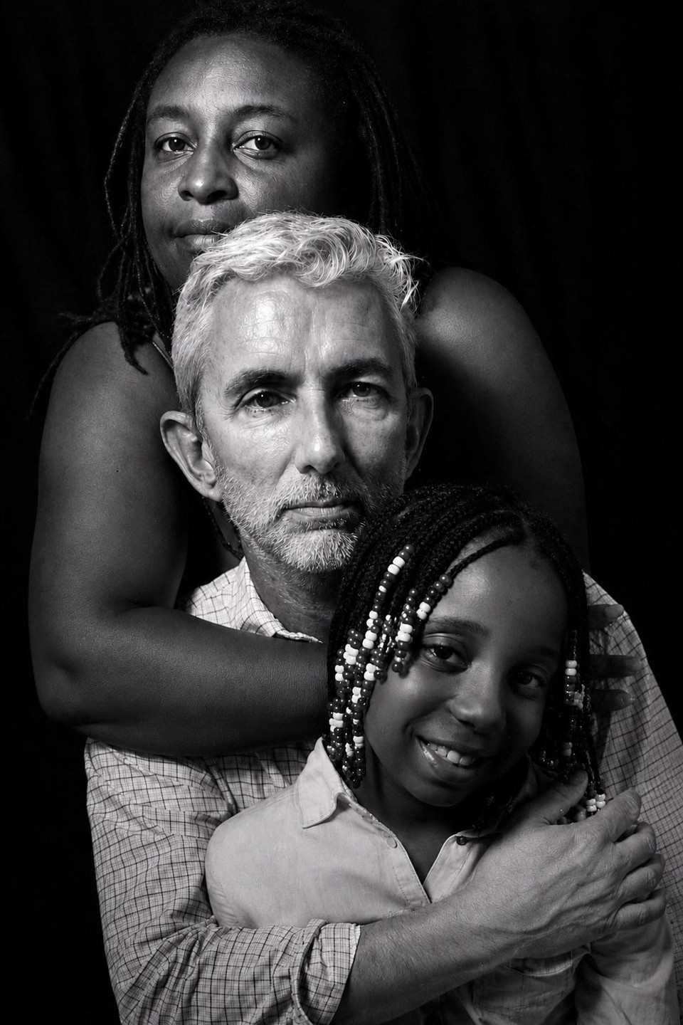 A woman, man, and girl are stacked vertically in a family portrait.