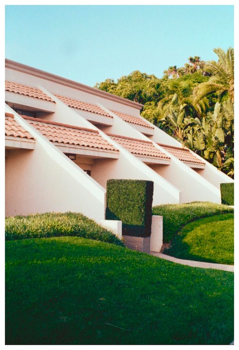 A resort building with a terracotta tile roof and green landscaping is visible under a clear sky.