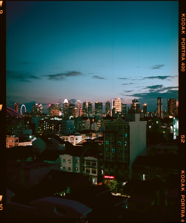A city skyline with illuminated buildings is visible at dusk, with a ferris wheel on the left.