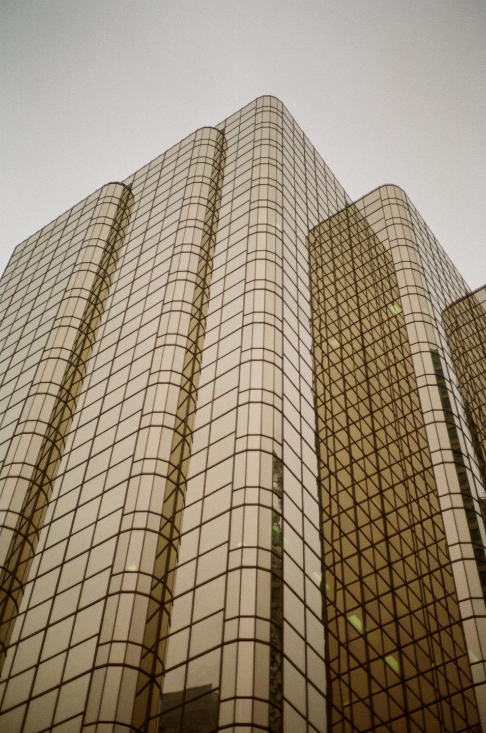 A tall building with golden glass windows reflects the sky.
