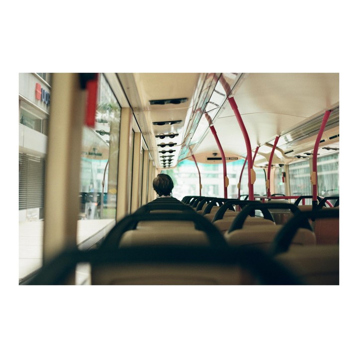 A person sits alone on a bus with empty seats stretching into the distance.