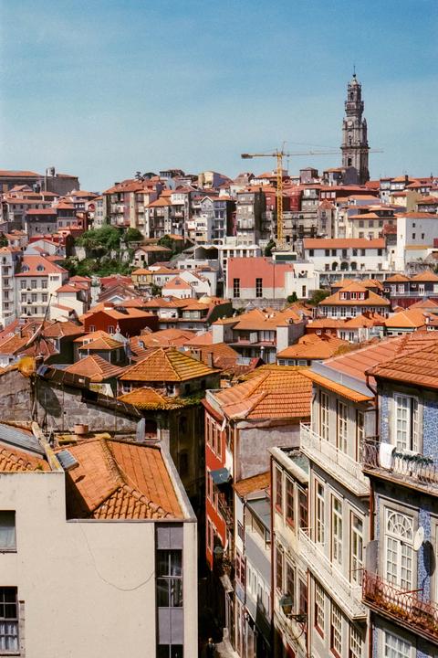 A dense hillside of buildings with orange tile roofs and a tall bell tower in the distance is visible under a clear sky.