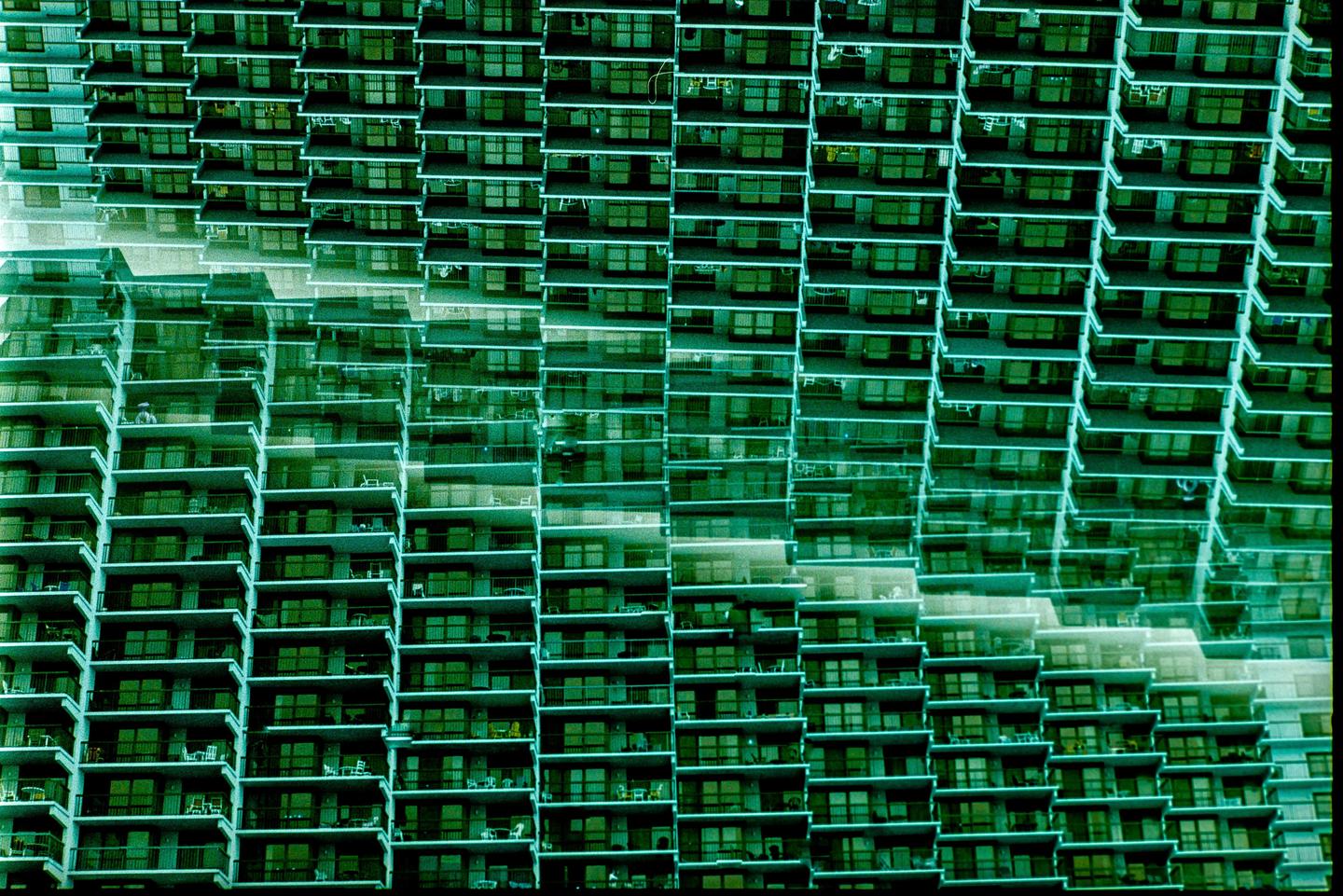 A green-tinted image shows a tall building with many balconies and windows, with a double exposure effect.