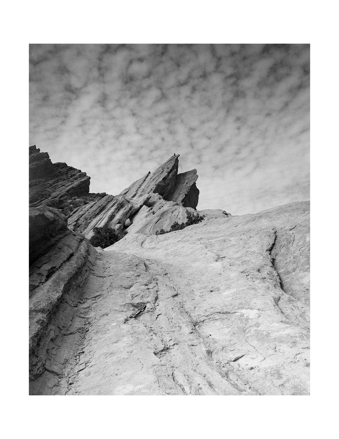 A low-angle view shows jagged rock formations under a cloudy sky.