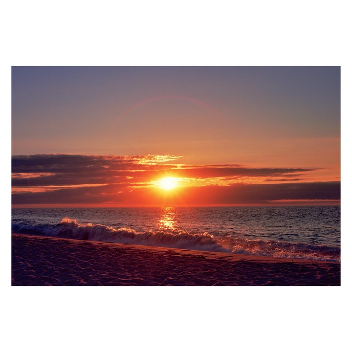 The sun sets over the ocean, casting an orange glow on the water and clouds.