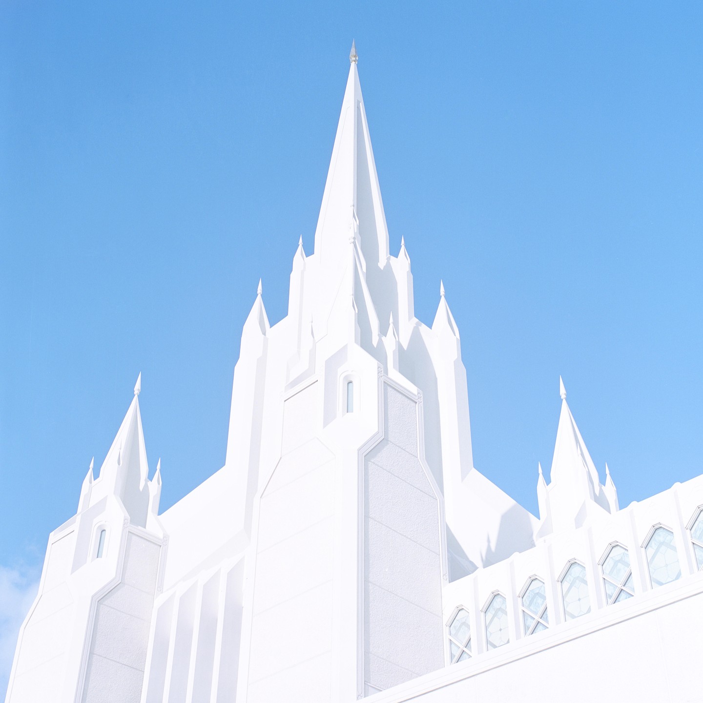 A white temple with multiple spires stands against a clear blue sky.